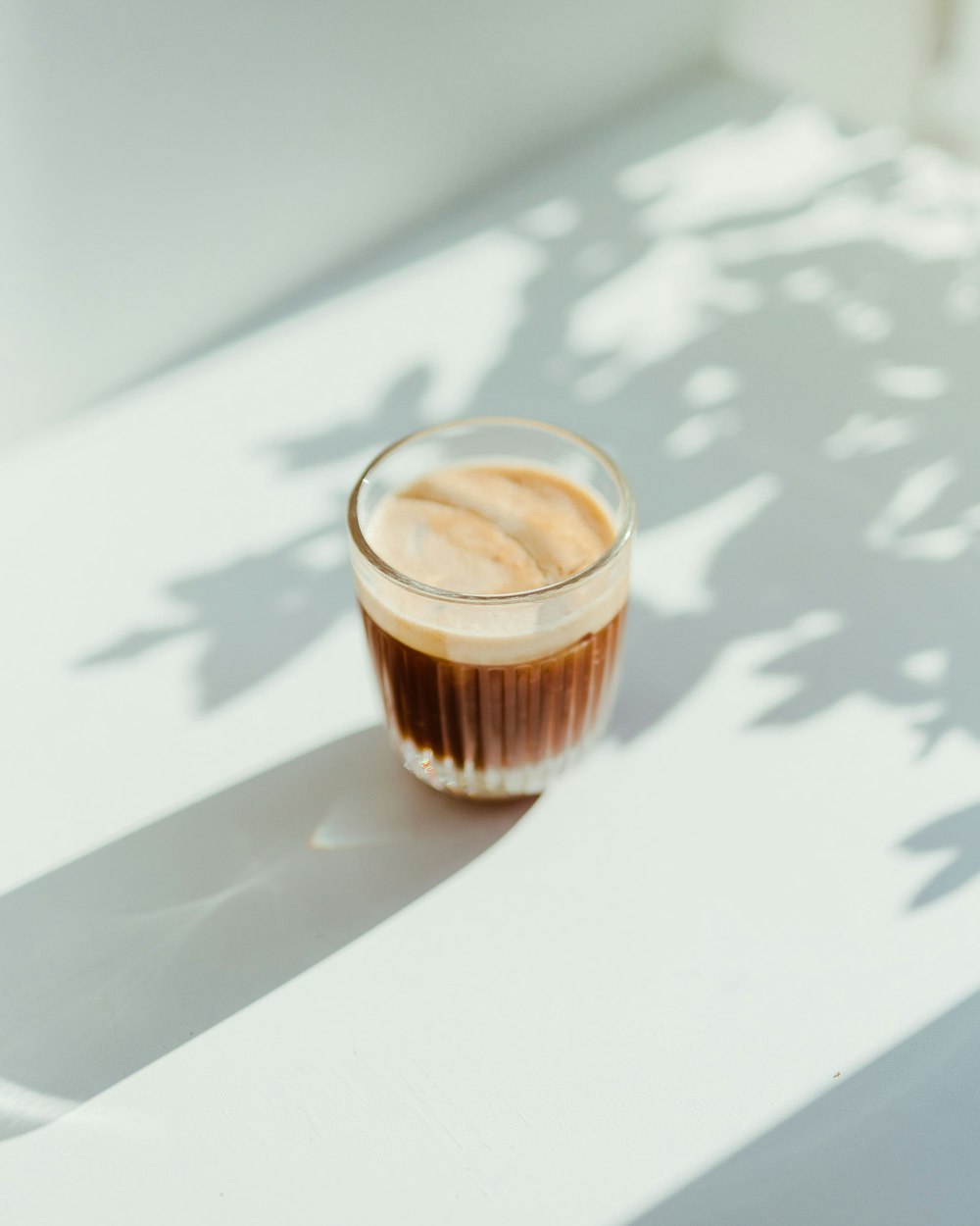 白背景に置かれたガラスカップのブラックコーヒー